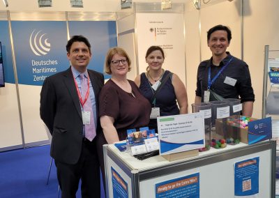 Vier Kolleg*innen stehen am DMZ-Messestand (links nach rechts: Dr. Matthias Catón, Kapt. Runa Jörgens, Dr. Katrin Maul, Johannes Puckelwald).