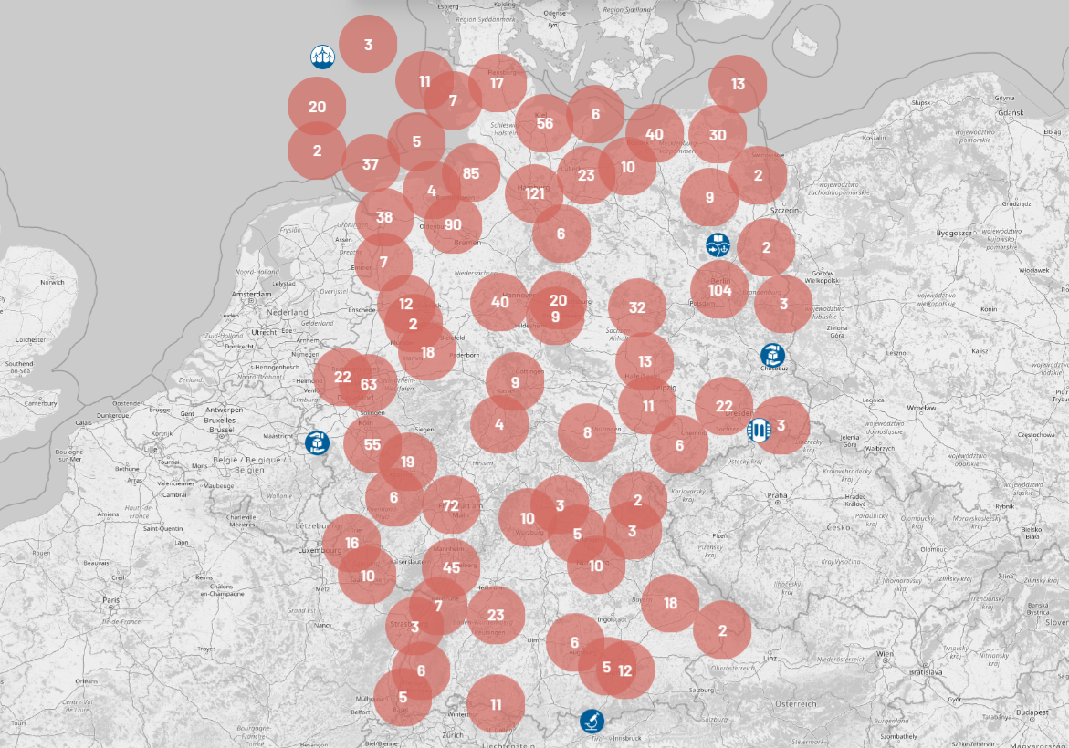 A grayscale map of northern Germany and surrounding areas displays red circular clusters with numbers, representing data points, and several blue icons indicating locations along the coastline and inland.